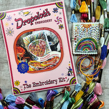 Load image into Gallery viewer, Dropcloth Embroidery Strawberry Needle Book kit. Each kit includes sampler for one needlebook, instructions, threads, wool for the inside lining, one snap, one ribbon, and a free trial for a Creativebug class.